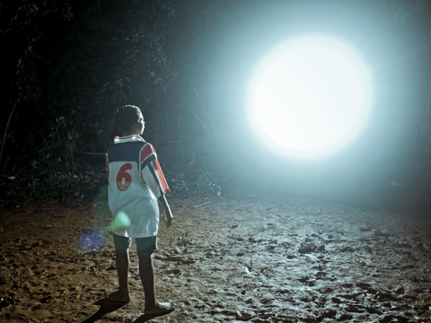 Caio plays football with other youth at the neighbour's football pitch