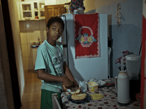 Caio watches TV while preparing his breakfast.