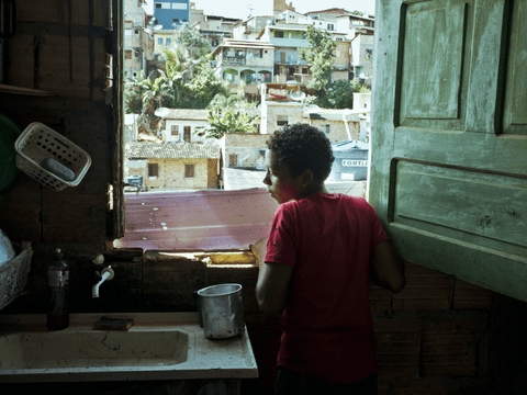 Caio stands at the window of his grandparents' kitchen in their home in the Bairro Novo favela.