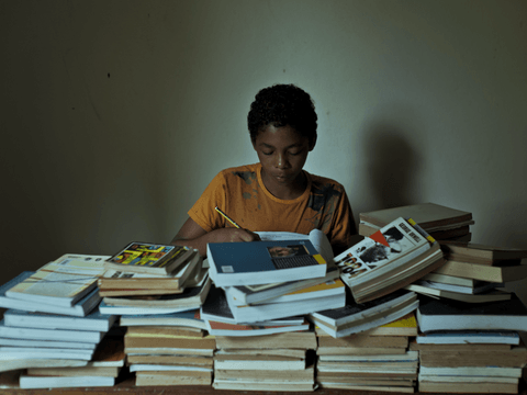 Caio completes a lesson in a workbook in his home.