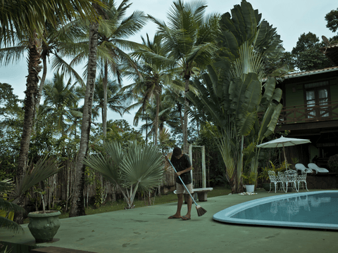 Caio sweeps a pool deck in the neighbourhood of Ribeirinha.