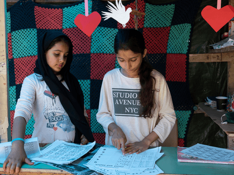 Manija (right), 13, prepares lessons at the “School of Stars” with the help of Naxila (left), 11.