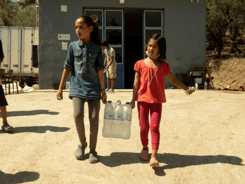 Atena (left) and Masha (right) carry water that they have just received for their families.