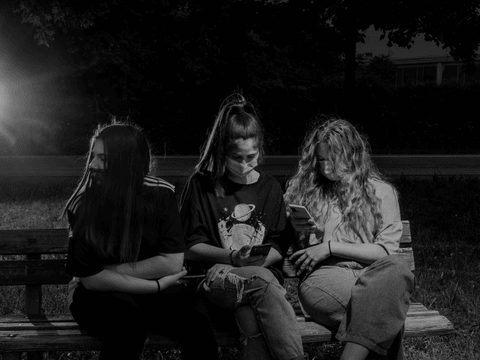Anna sits with her best friends, Clarissa and Chiara, in the park near to Anna's home.