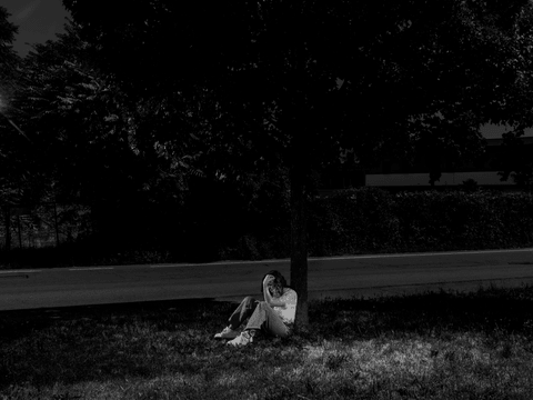 Anna flips through her phone in the park near her home.