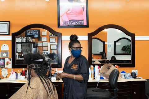 Elaine braids a customer's hair in her hair salon in Brooklyn, New York.